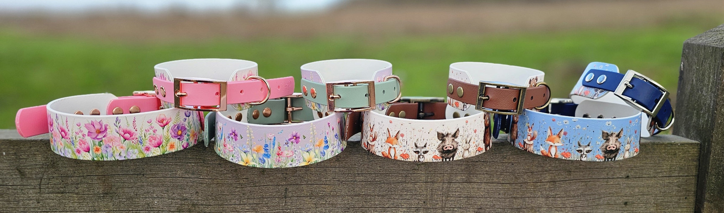 A colourful range of patterned Trinkety Paws collars on a fence outdoors